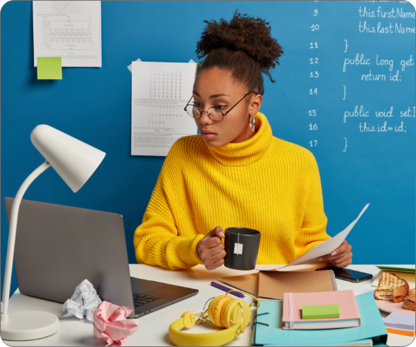 serious-dark-skined-woman-checks-information-from-papers-laptop-watches-training-webinar-about-computer-programming