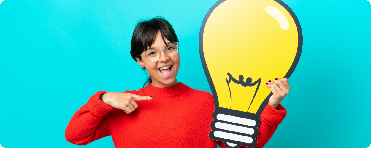 young-woman-isolated-blue-background-holding-bulb-icon-pointing-it